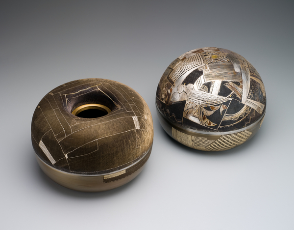 Covered rice bowl, male bowl, one of pair. The male rice bowl has a domed lid, and both the lid and bowl are densely covered in intricate patterns, using gold, silver and odong (a copper-gold alloy, similar to Japanese shakudo) inlaid wire, with a blue-black oxidised steel background. The inlaid patterns are inspired by Korean Joseon dynasty bojagi (wrapping cloths). Covered rice bowl, female bowl, one of pair. The female rice bowl has a hole in the centre of its lid, and is decorated with silver, gold and bronze inlaid wire against a blue-black oxidised steel background. The inlaid patterns are inspired by Korean Joseon dynasty bojagi (wrapping cloths) and the chisel marks covering the surface give the appearance of fabric. 